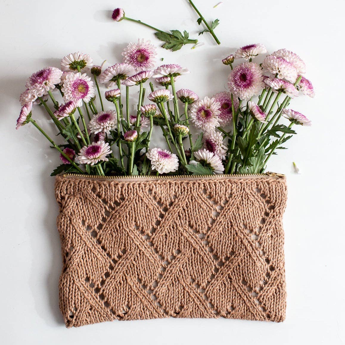 Knitted Rowan pouch with a pattern filled with pink flowers on a white background