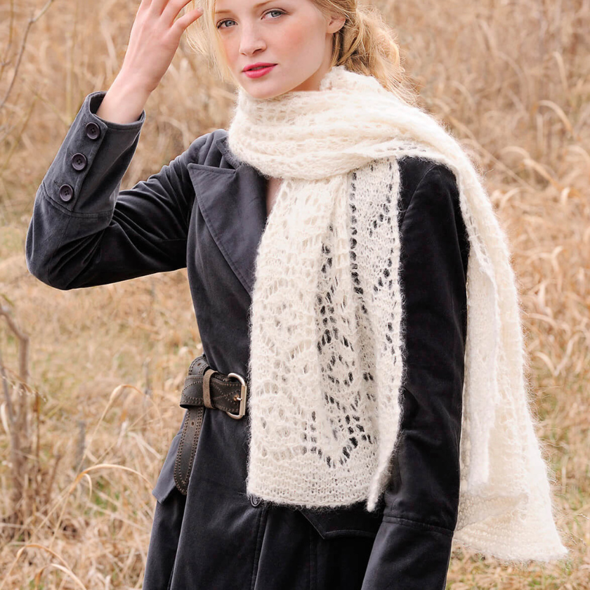 Woman wearing a black coat and white Brushed Suri scarf in a natural setting