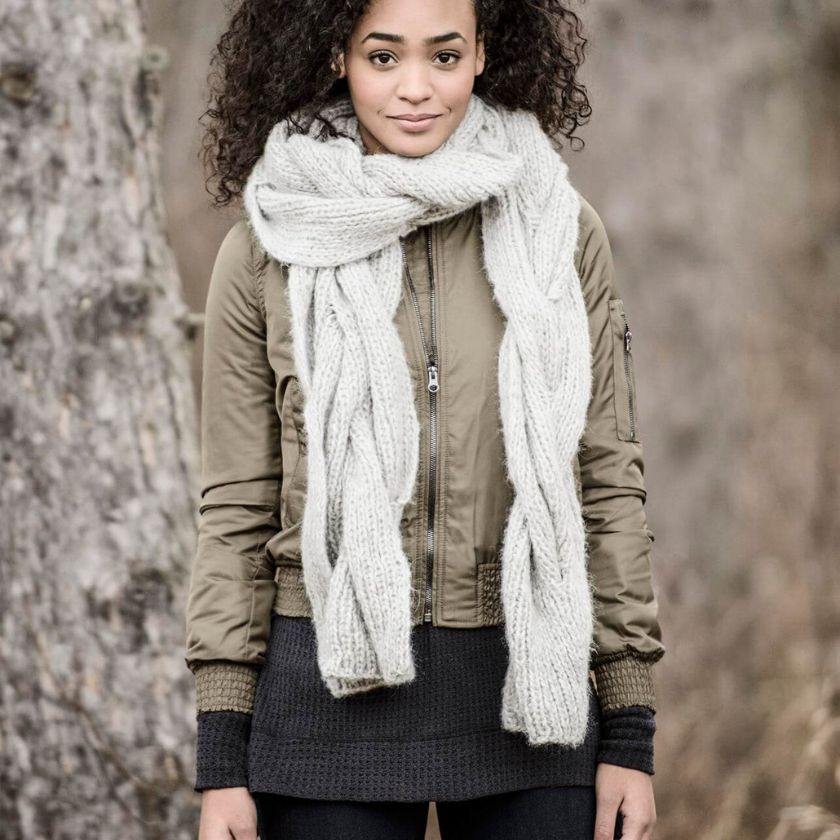 Woman wearing a beige jacket and a Metro Silver Techno Callaway Cable scarf in a natural setting.