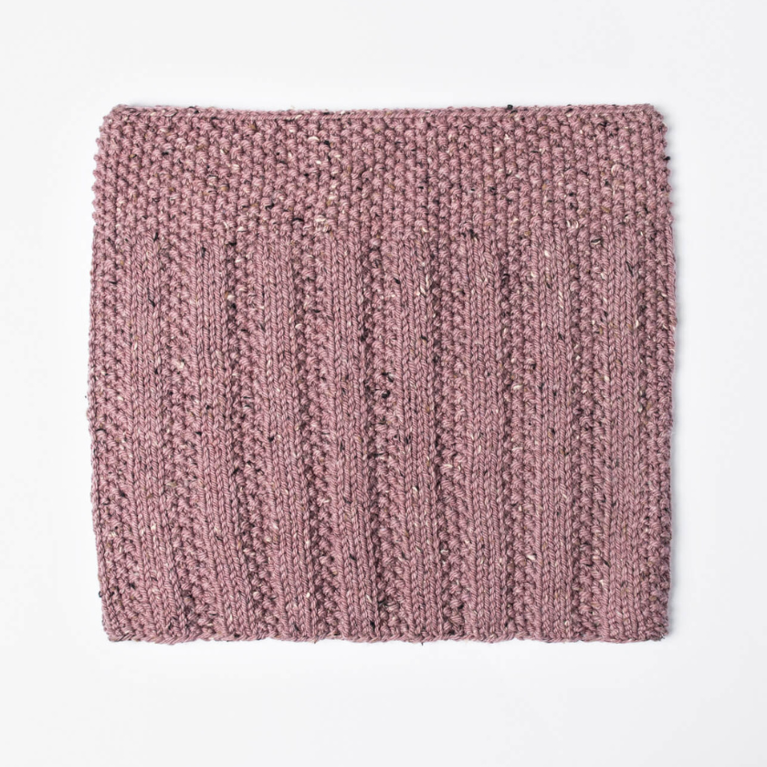 Flat lay of the Lulu Cowl knit cowl highlighting the ribbed stitch pattern and tweed texture of Woolstok Tweed yarn.