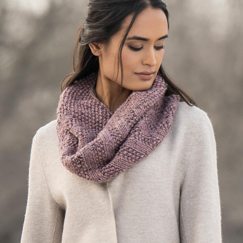 Model wearing the Lulu Cowl knit cowl in Woolstok Tweed Aran, styled close to the neck with a soft ribbed texture.