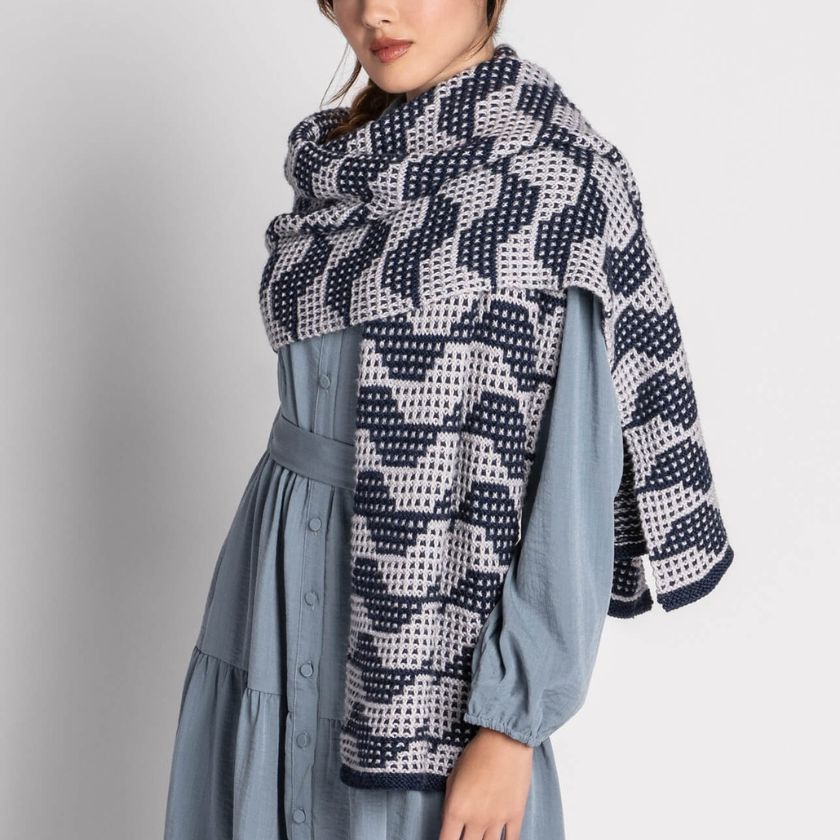 Woman wearing a blue dress with a Market Street Wrap on a plain background