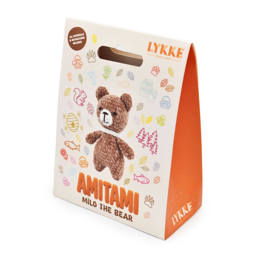 Packaging of an Amitami teddy bear knitting kit with 'LYKKE' branding on a white background