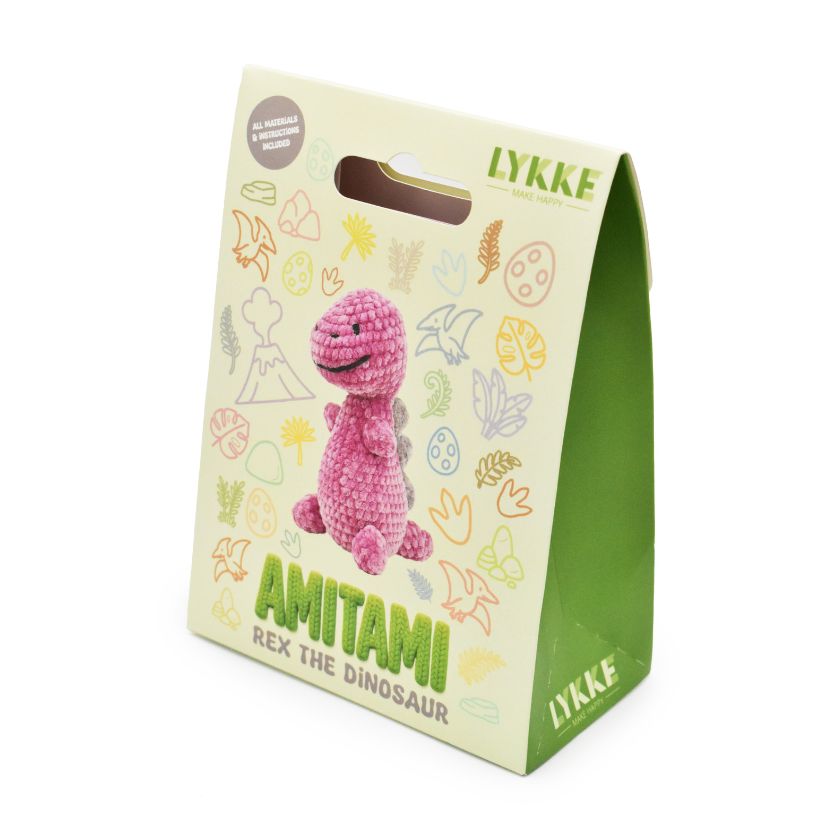 Packaging of an Amitami dinosaur knitting kit with 'LYKKE' branding on a white background