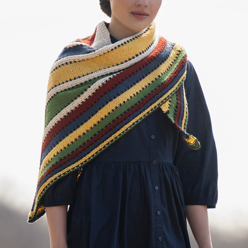Model wearing the Camp Ivanhoe Shawl Kit in Blue Sky Fibers Organic Cotton Sport, shown from the front with colorful vintage-inspired stripes.