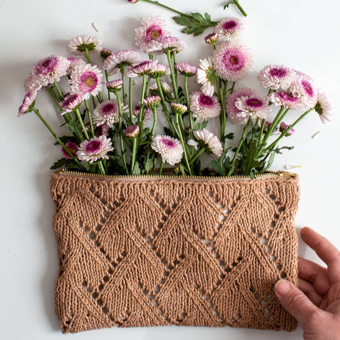 Handmade knitted Rowan pouch with flowers on a white background