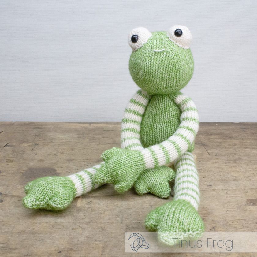 Knitted Amigurumi Tinus Frog toy, a green toy frog with striped arms