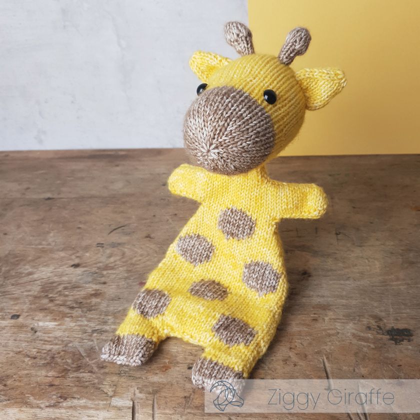 Knitted Ziggy Giraffe toy by Amigurumi on a wooden surface with a yellow background