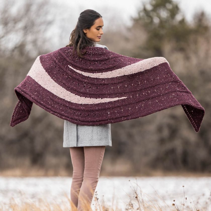 Back view of model wearing the Kelso Wrap, displaying full wingspan and bold striped sections across the shoulders.