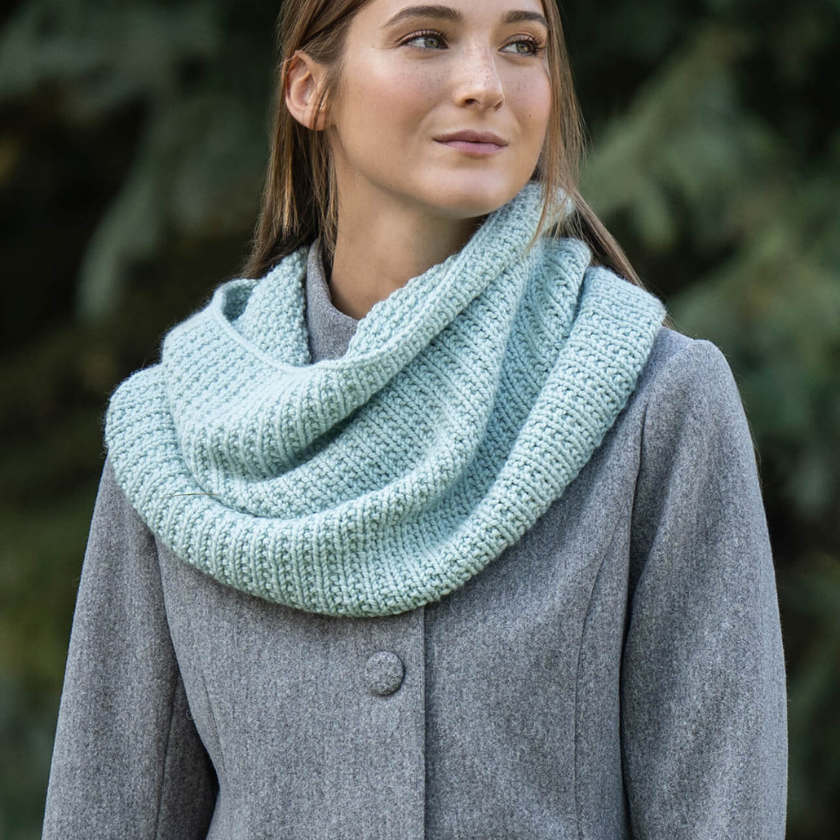 Mist Cowl knit in Blue Sky Fibers Extra Aran worn layered over a gray coat showing soft drape and textured stitch pattern, The Dizzy Knitter