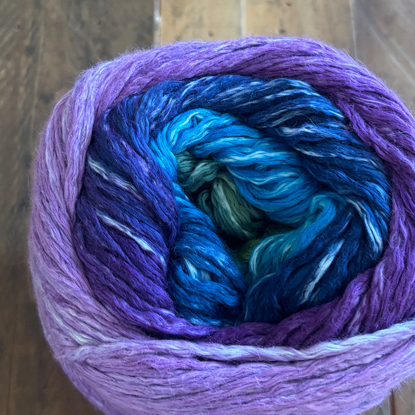 Ball of Moonlight Jewel Culumus Rainbow yarn on a wooden surface