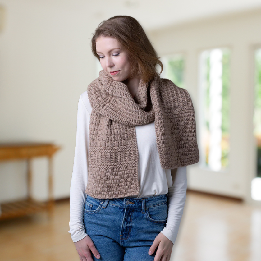 Woman wearing a long brown knitted Pascuali Mix it Up scarf indoors