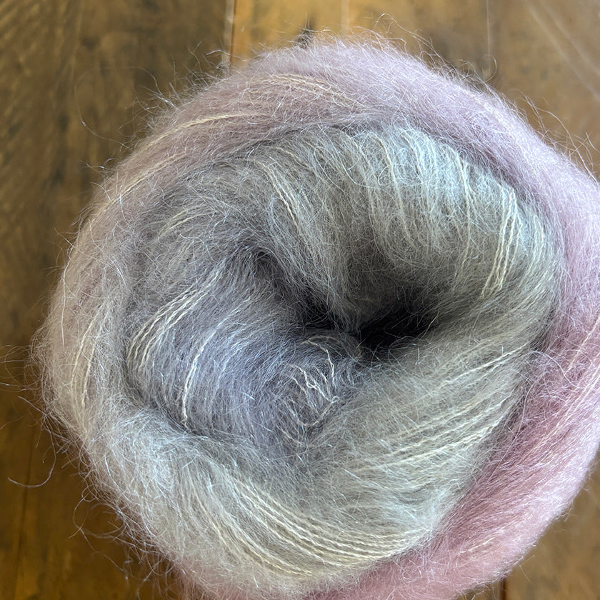 Ball of Poema Mohair yarn in Pink, Silver, and Taupe on a wooden surface