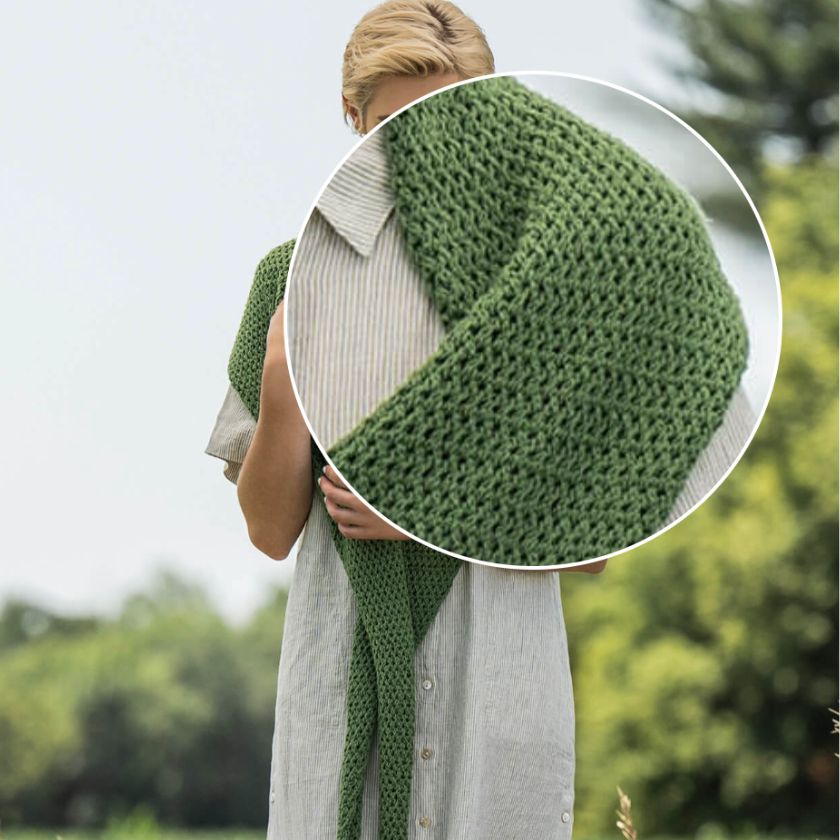 Person wearing a green knitted scarf with a close-up of the scarf's texture.