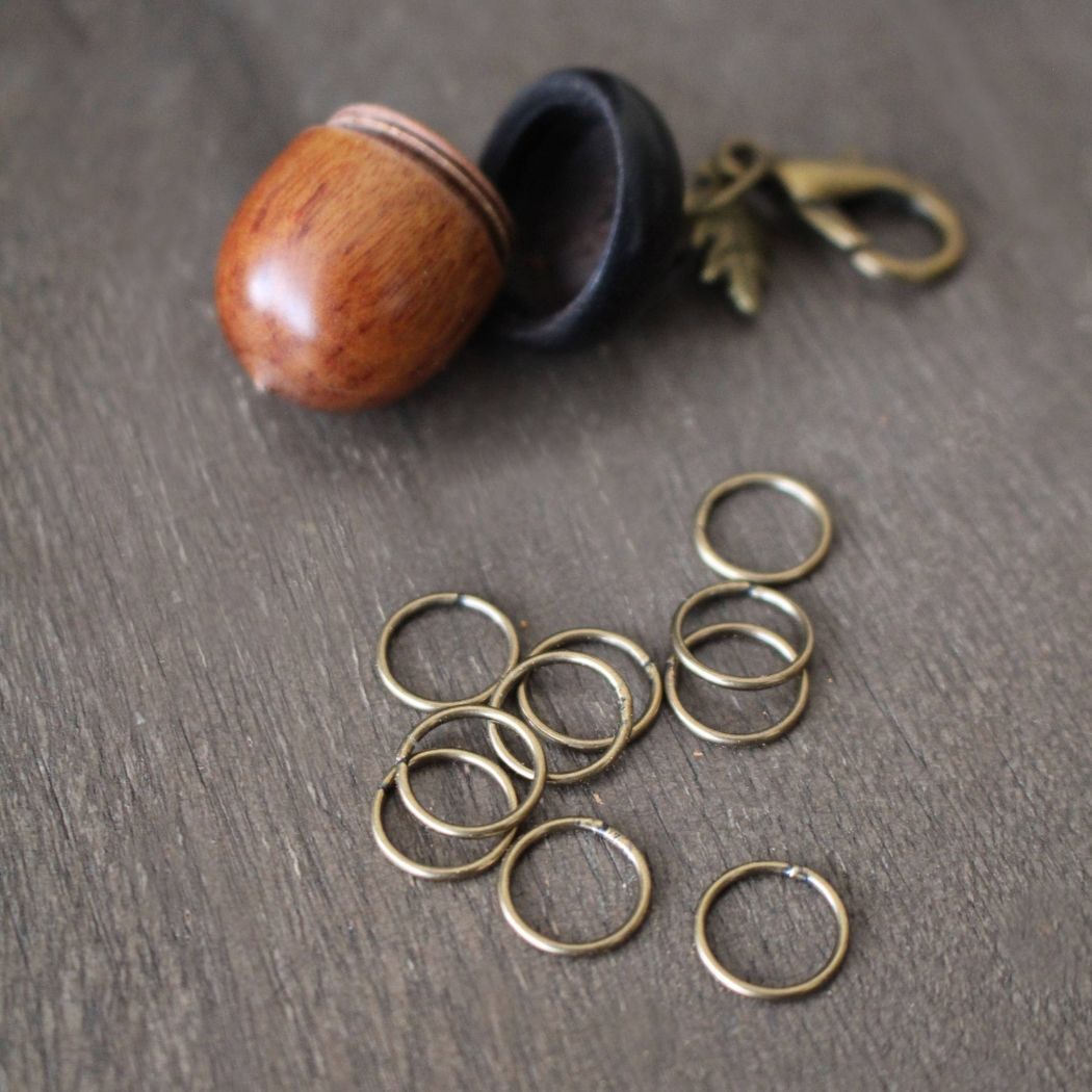 Metal stitch markers next to an acorn shaped stitch marker holder