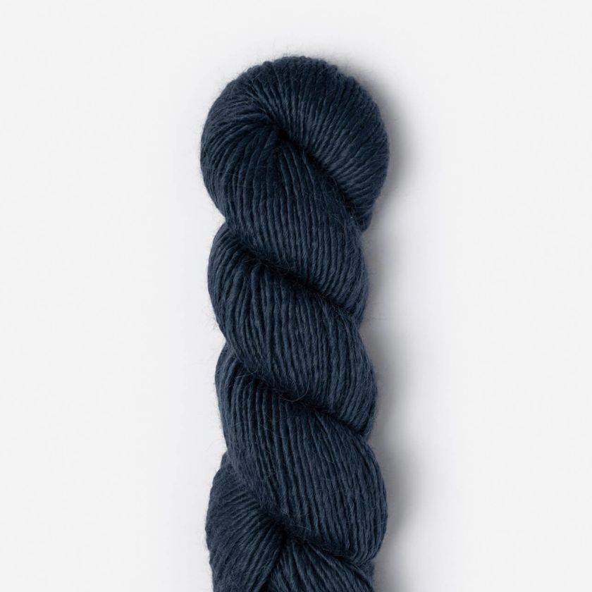 Dark blue skein of Suri Merino yarn in Abyss on a light gray background
