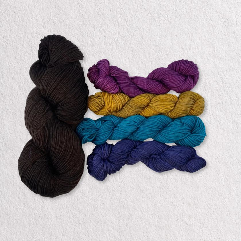 Five skeins of yarn in black, purple, yellow, blue, and navy on a white background