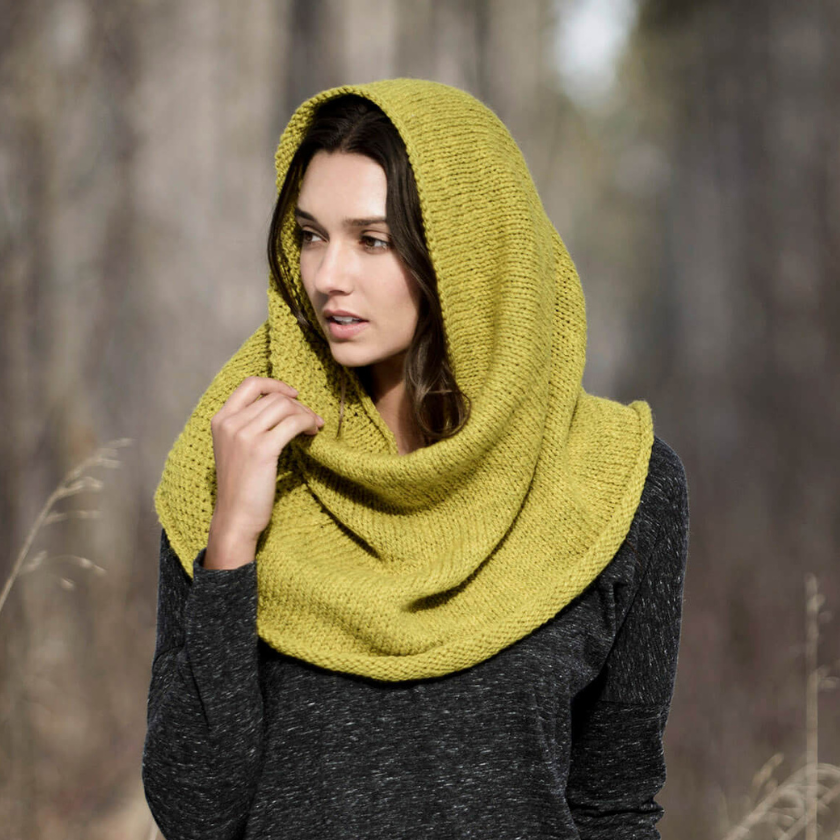 Trimont Snood worn hooded, offering cozy warmth and versatile wear in a natural setting