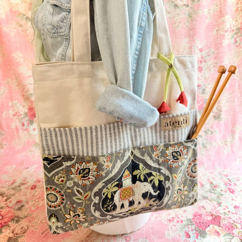 Tutto Atenti tote bag with floral and elephant pattern, held by a person wearing a denim jacket.